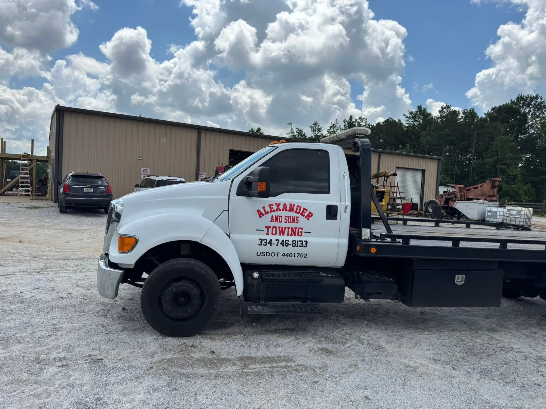 The Alexander and Sons Towing Ford F-650 rollback flatbed parked at a yard