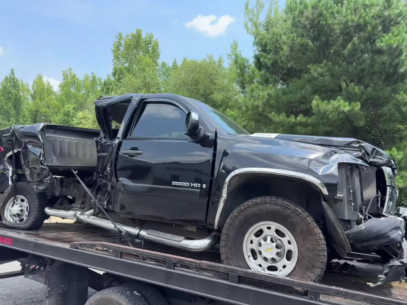 A heavily damaged GMC Sierra 2500HD loaded and secured after a collision.