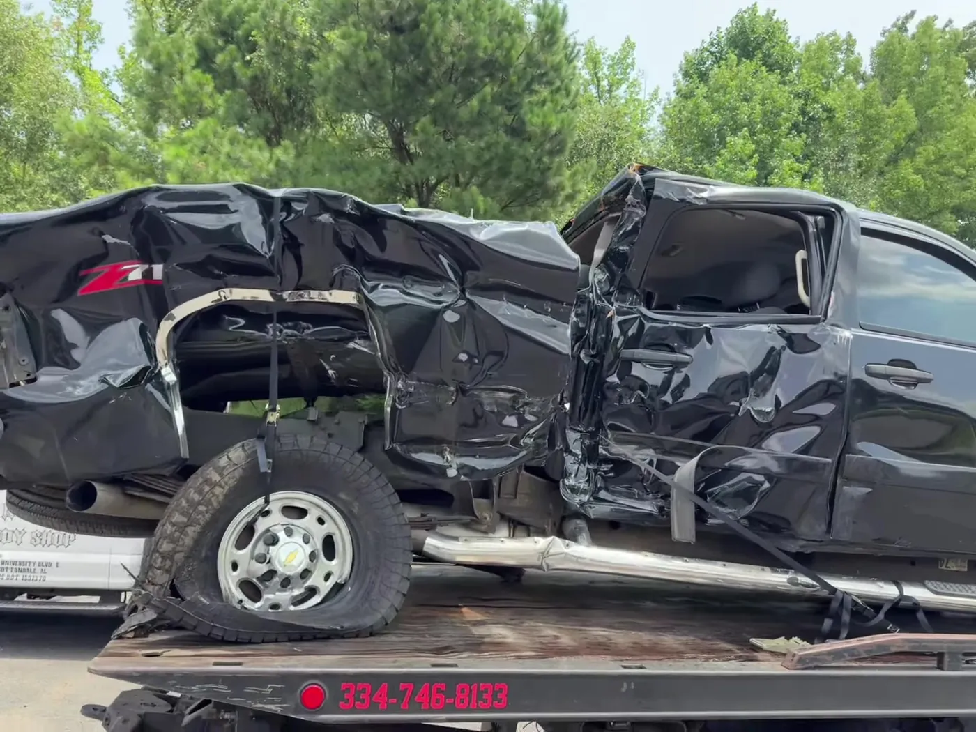 Rear quarter of the same wrecked Sierra, strapped and stable on the deck.